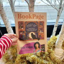 Hand holding up an issue of Book Page